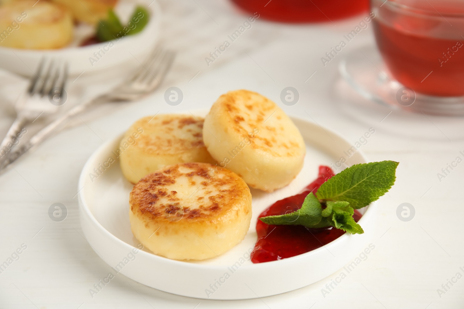 Photo of Delicious cottage cheese pancakes with jam and mint on white table