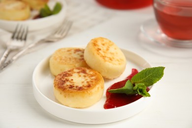 Photo of Delicious cottage cheese pancakes with jam and mint on white table