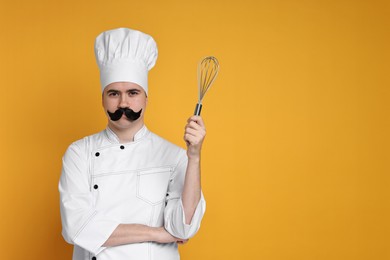 Photo of Portrait of happy confectioner with funny artificial moustache holding whisk on orange background, space for text