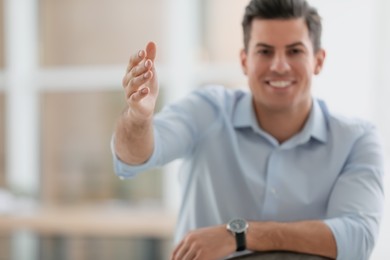 Photo of Businessman reaching out for handshake in office, focus on hand