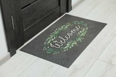 Photo of Doormat with word Welcome on white floor near entrance