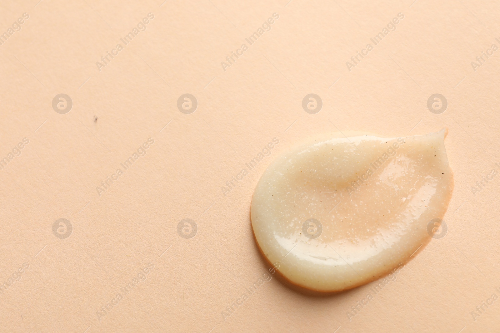 Photo of Sample of scrub on pale orange background, top view. Space for text