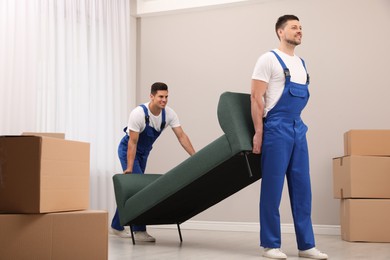 Professional movers carrying sofa in new house