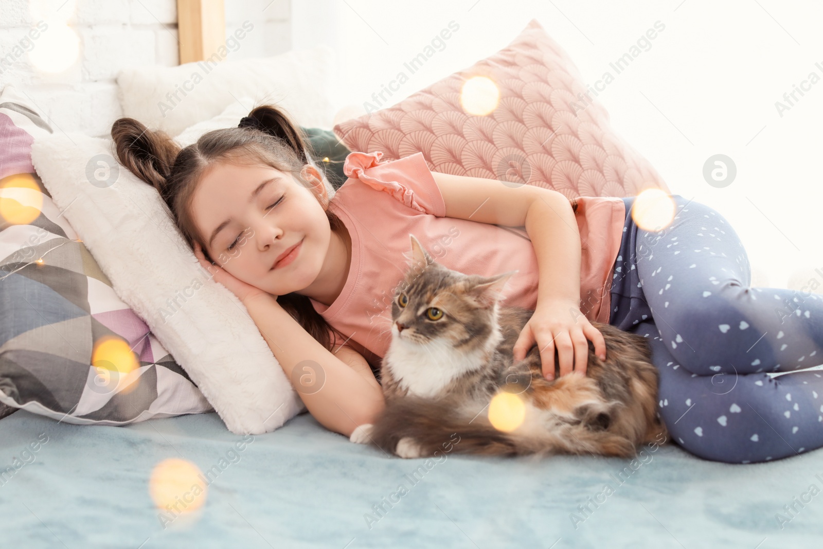 Photo of Cute little girl with cat lying on bed at home