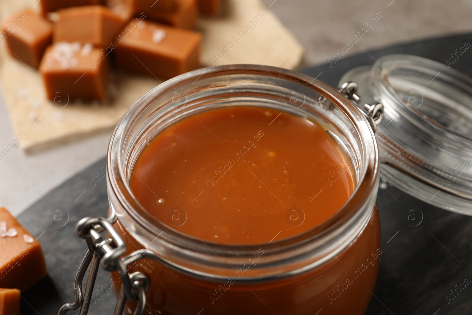 Photo of Tasty salted caramel in glass jar on table, closeup