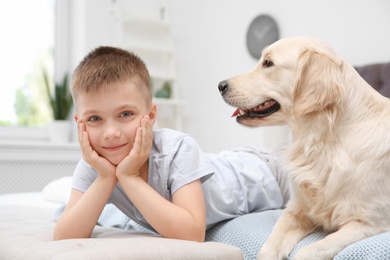 Cute little child with his pet on bed at home