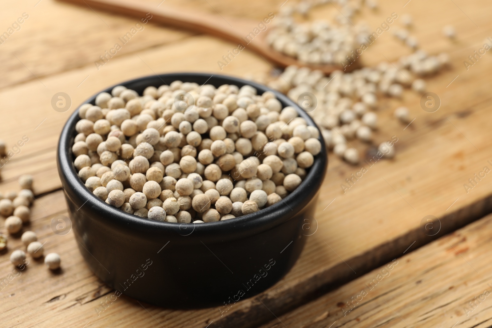 Photo of Aromatic spice. White pepper in bowl on wooden table, closeup