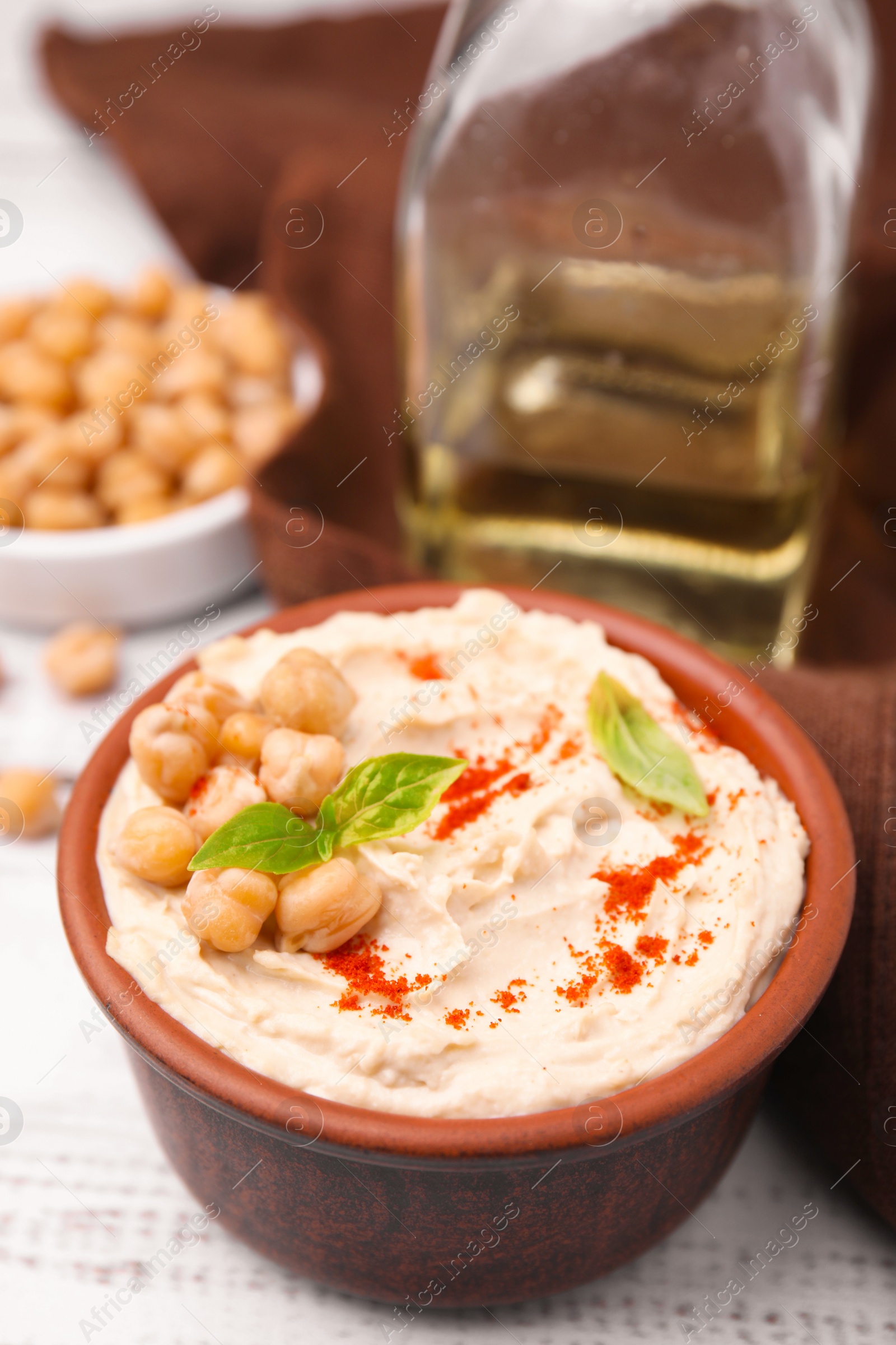 Photo of Delicious hummus with chickpeas and paprika served on white wooden table, closeup