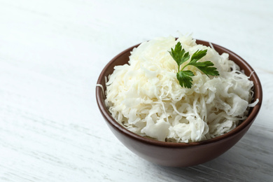 Photo of Tasty fermented cabbage on wooden table, closeup