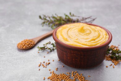 Photo of Bowl with delicious mustard and seeds on light grey table, closeup. Space for text