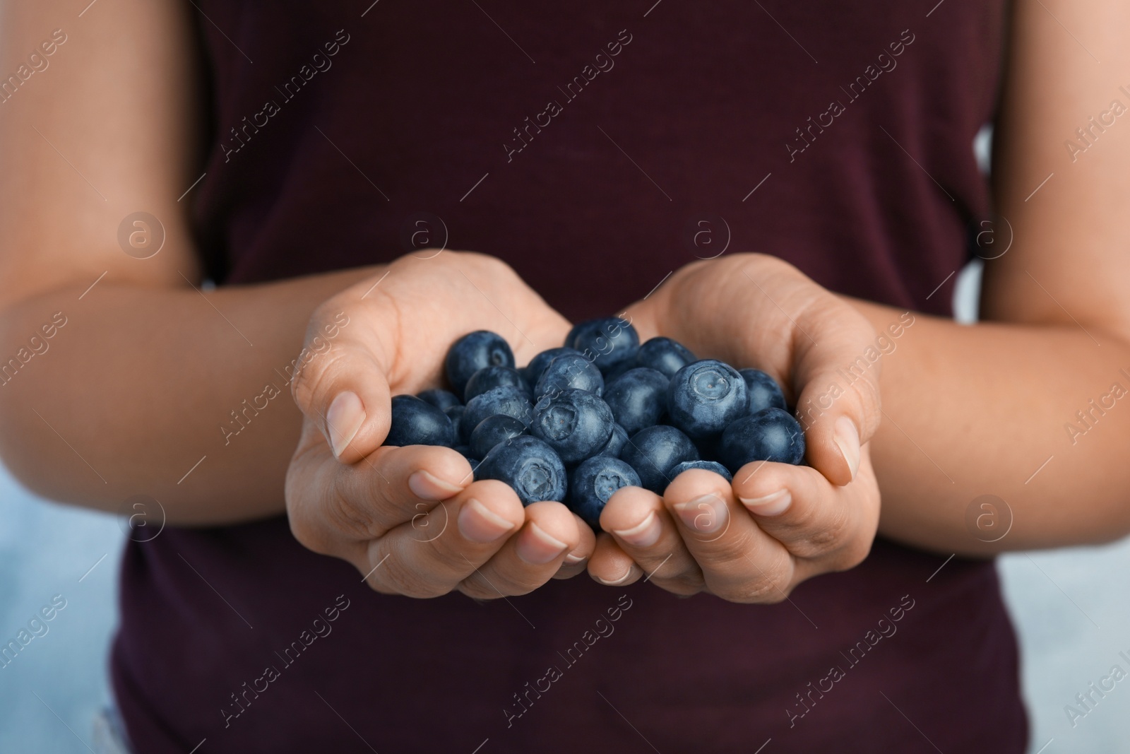 Photo of Young woman holding tasty ripe blueberries, closeup