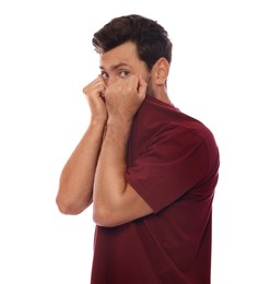 Embarrassed man covering face with shirt on white background