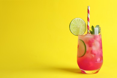 Photo of Tasty summer watermelon drink with lime in glass on yellow background. Space for text