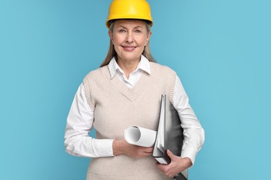 Photo of Architect in hard hat with draft and folder on light blue background