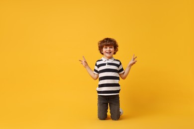 Happy little boy dancing on yellow background. Space for text