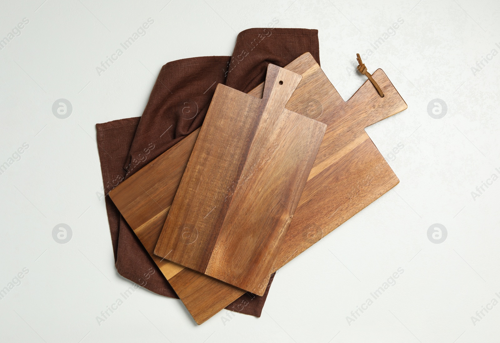 Photo of Wooden boards and napkin on white background, top view. Cooking utensils