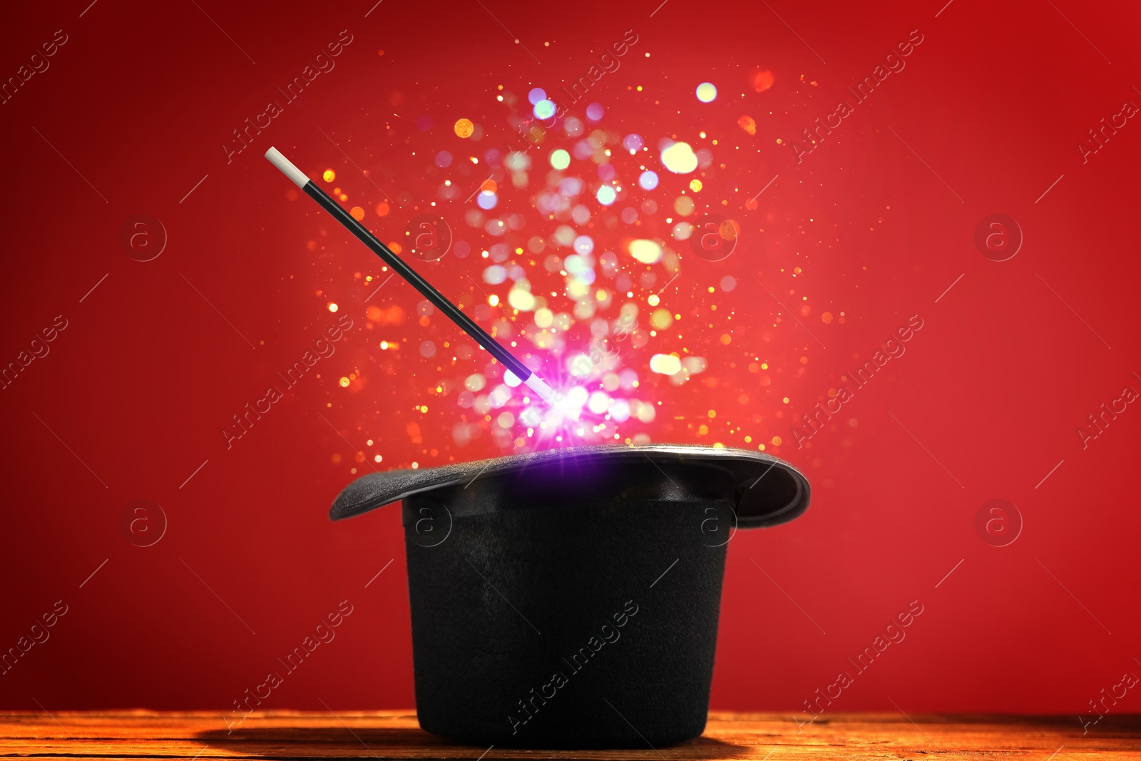 Image of Wizard's hat with wand and magical light on red background