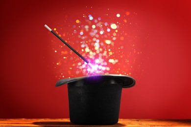 Image of Wizard's hat with wand and magical light on red background