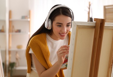 Photo of Beautiful young woman listening to music while drawing at home