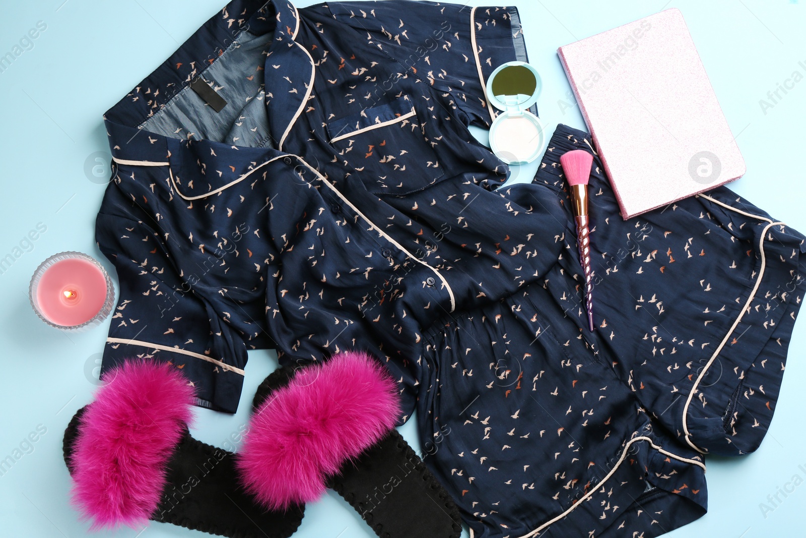 Photo of Flat lay composition with fluffy slippers and pajamas on light blue background. Comfortable home outfit