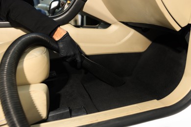 Man cleaning auto carpet with vacuum cleaner at car wash, closeup