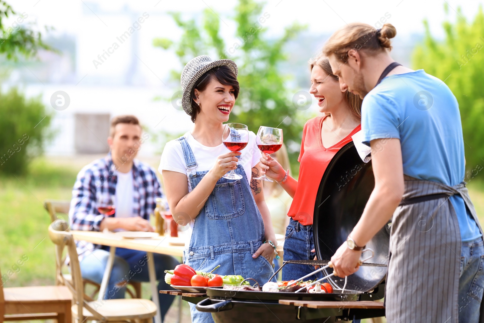 Photo of Young people having barbecue with modern grill outdoors