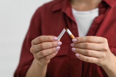 Photo of Stop smoking concept. Woman breaking cigarette on light background, closeup