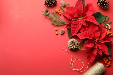 Photo of Flat lay composition with poinsettias (traditional Christmas flowers) and decor on red background. Space for text