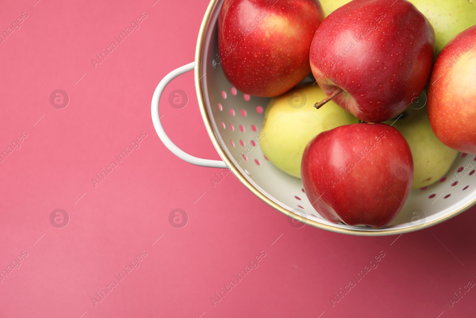 Photo of Colander with fresh apples on pink table, top view. Space for text