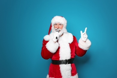 Photo of Santa Claus singing into microphone on color background. Christmas music