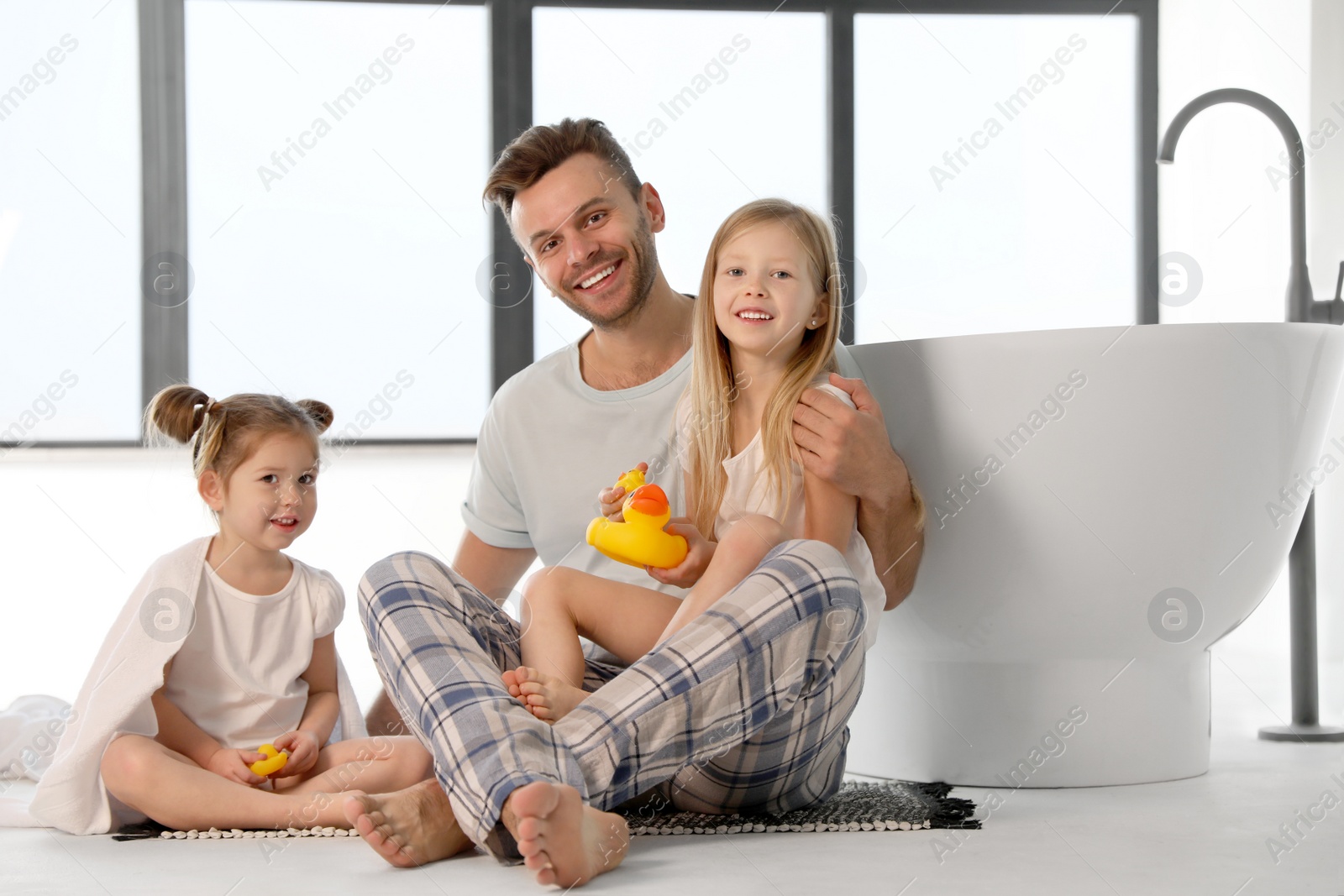 Photo of Father with little daughters near tub in bathroom