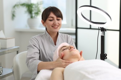 Cosmetologist making face massage to client in clinic