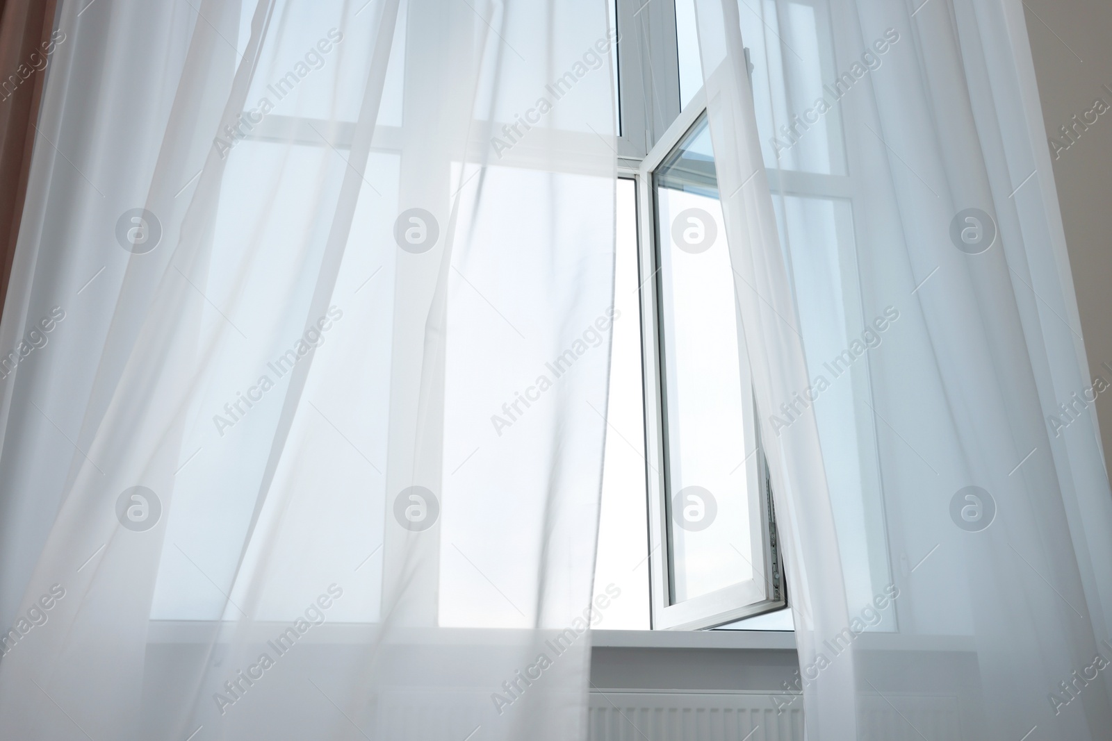 Photo of Open window and elegant white curtains indoors. Interior design