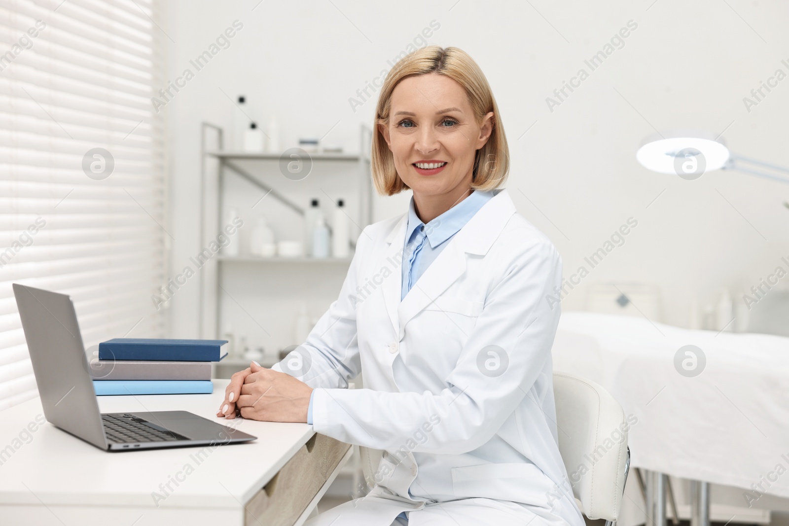 Photo of Portrait of happy dermatologist at white table in clinic