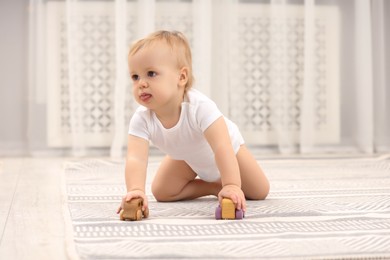 Photo of Children toys. Cute little boy playing with wooden cars on rug at home