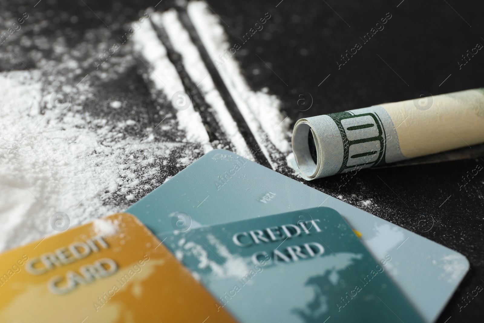 Photo of Cocaine, credit cards and rolled dollar banknote on black background