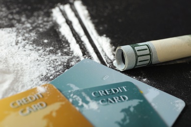 Photo of Cocaine, credit cards and rolled dollar banknote on black background