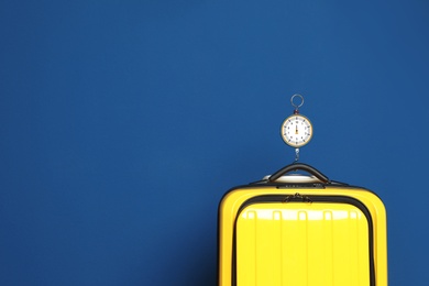 Photo of Modern suitcase and hanging scales against color background, space for text