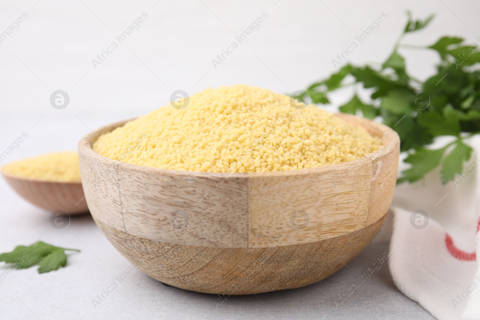 Photo of Raw couscous in wooden bowl on table, closeup