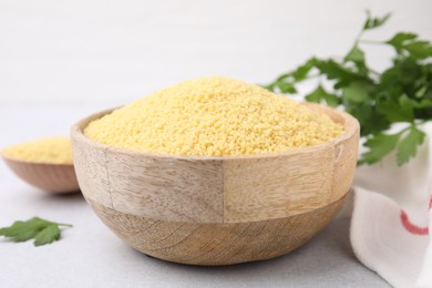 Photo of Raw couscous in wooden bowl on table, closeup