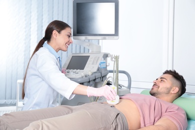 Doctor conducting ultrasound examination of patient's abdomen in clinic