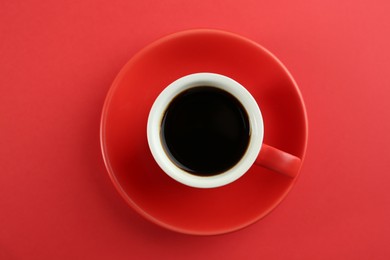 Photo of Cup of tasty coffee on red background, top view
