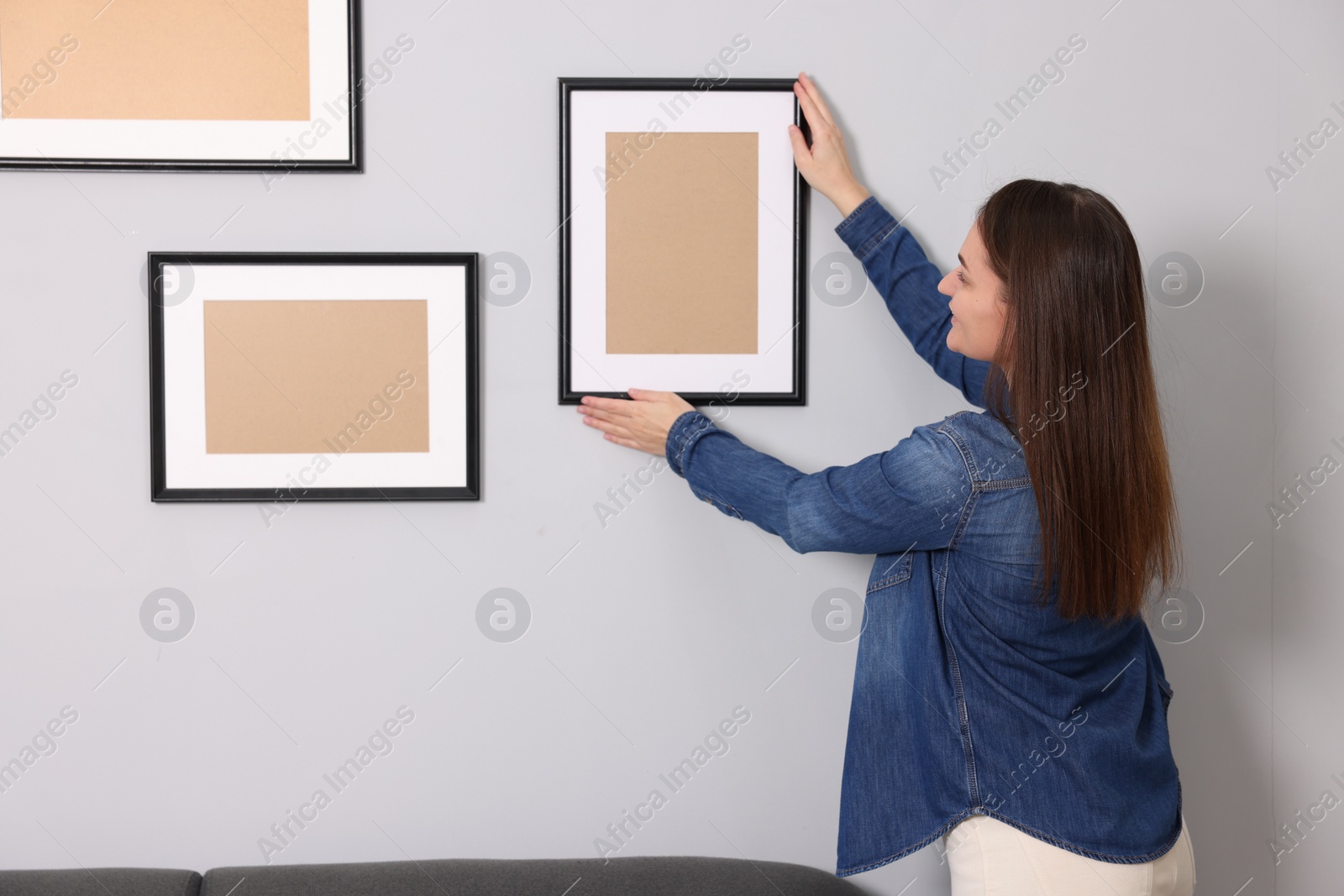 Photo of Woman hanging picture frame on gray wall