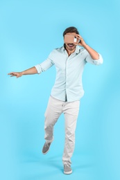 Young man using cardboard virtual reality headset on color background