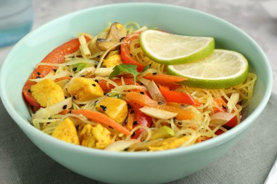 Photo of Stir-fry. Delicious cooked noodles with chicken and vegetables in bowl on table, closeup