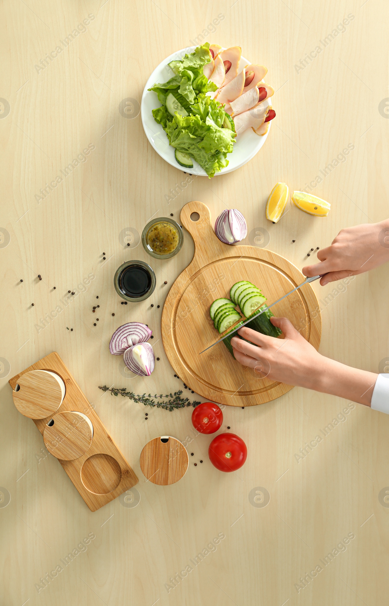 Photo of Woman cooking food at wooden kitchen table, flat lay