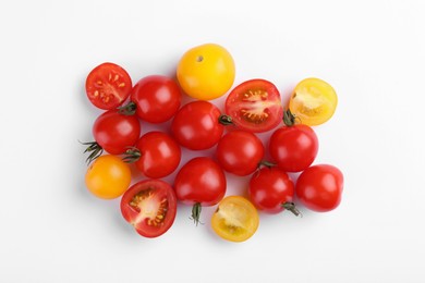 Different whole and cut tomatoes on white background, flat lay
