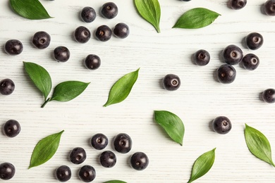 Photo of Flat lay composition with fresh acai berries and leaves on wooden background