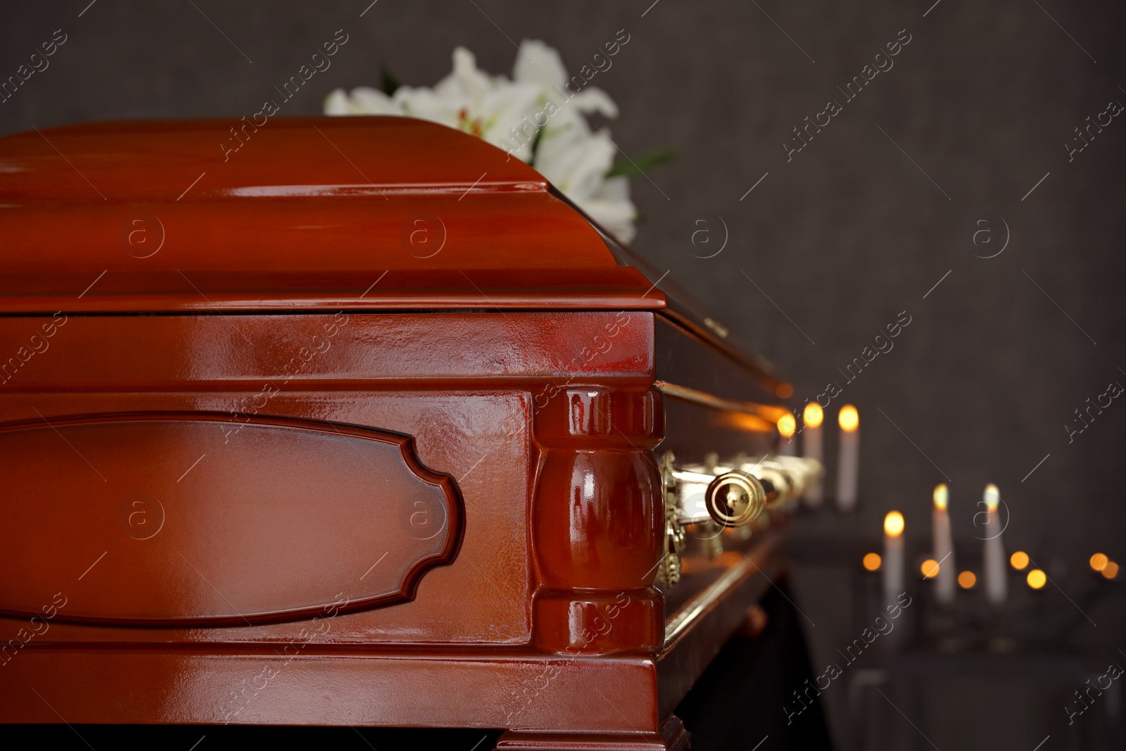 Photo of Wooden casket with white lilies in funeral home, closeup