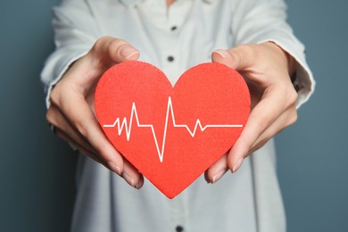 Image of Woman holding red heart with cardiogram, closeup 